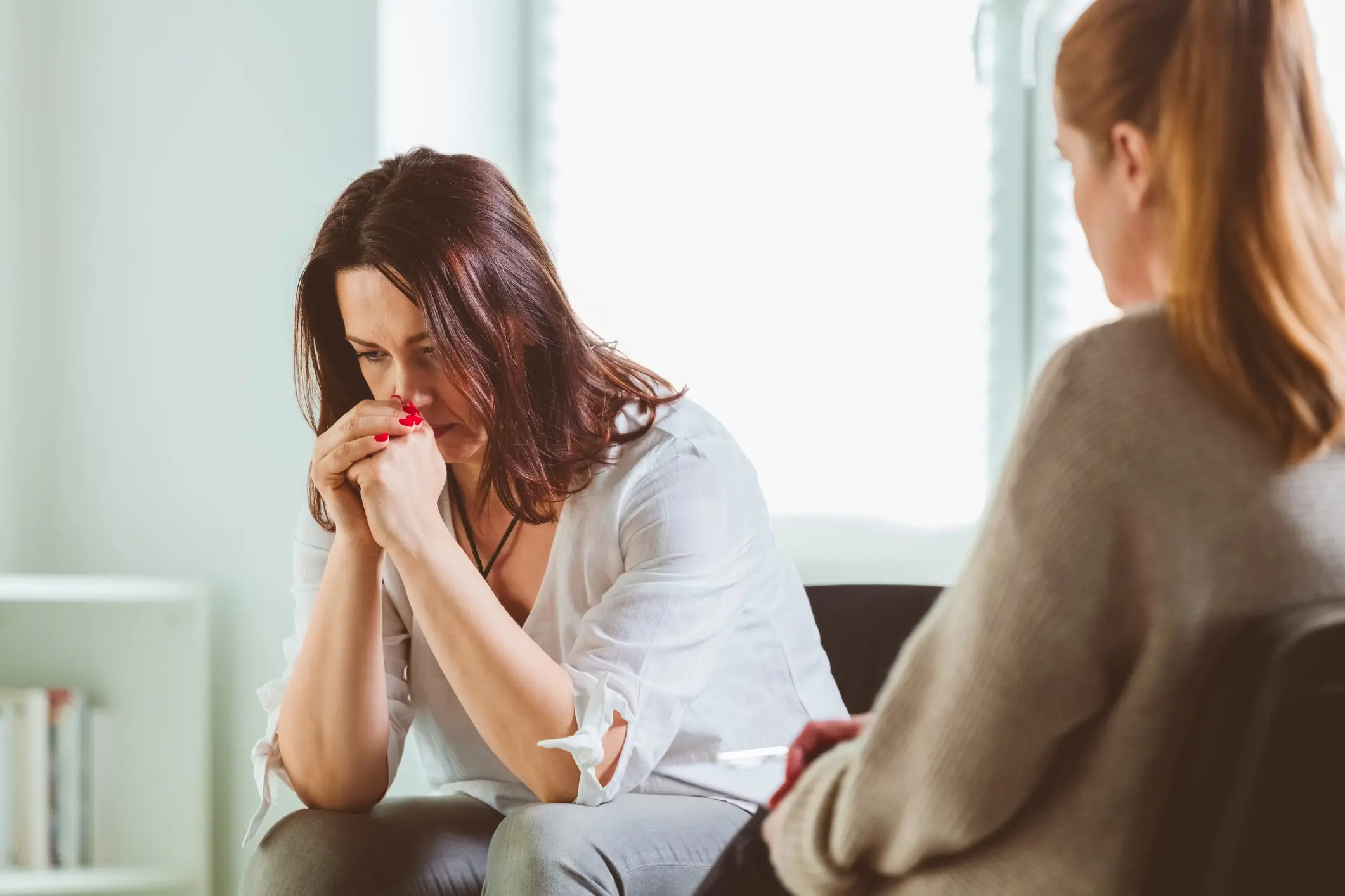 Woman leans forward in her chair and resting her head in her hands during a therapy session