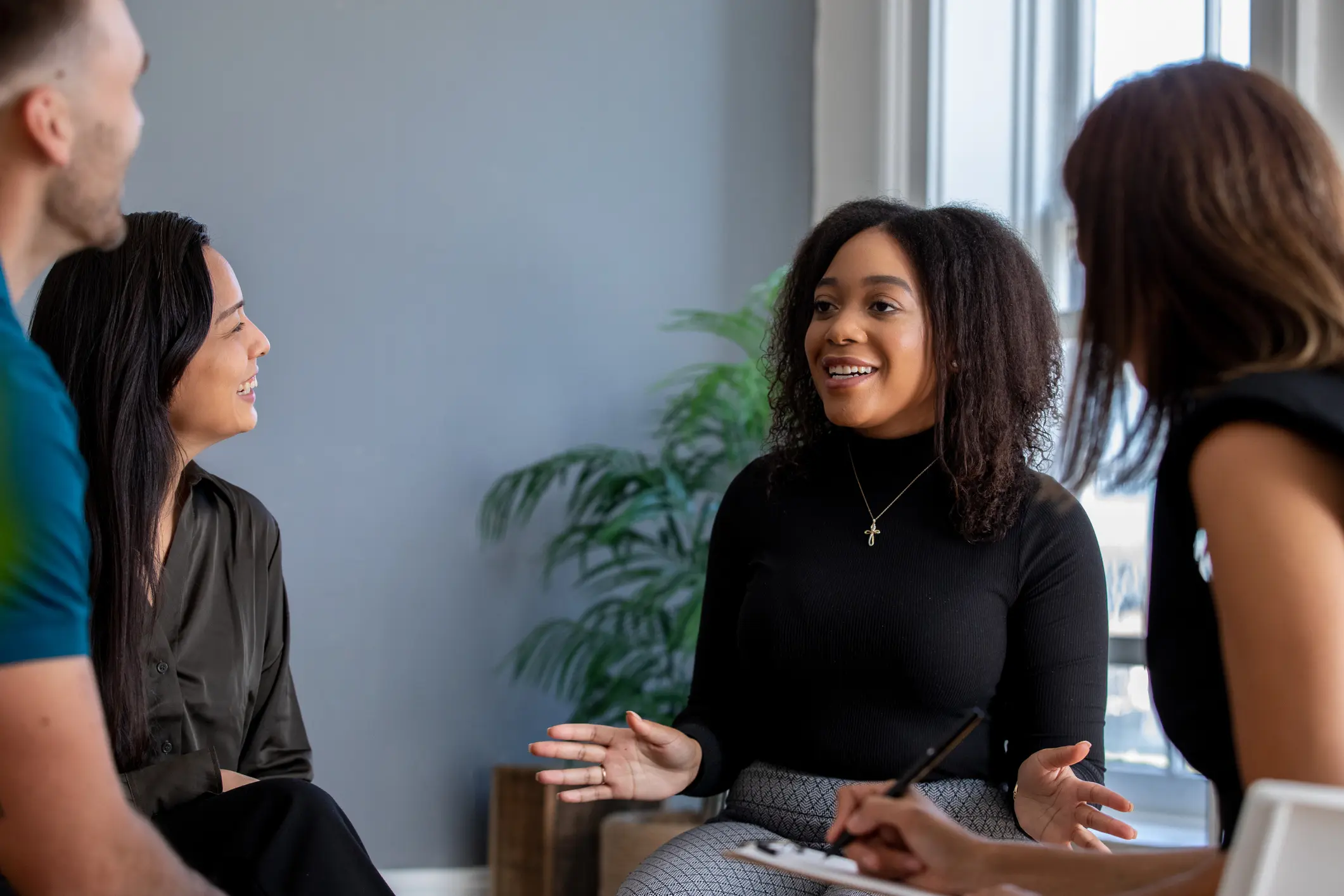 A woman smiles while surrounded by peers in group therapy.