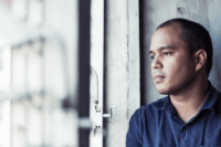 Man staring pensively out a window.