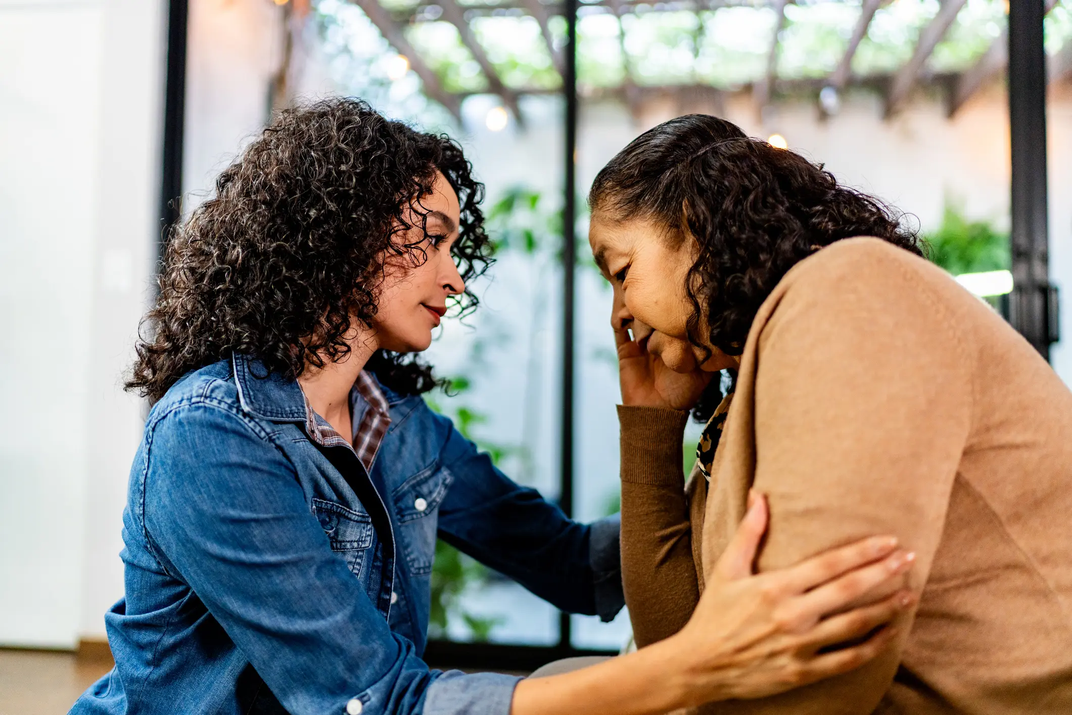 Young woman consoling mother at home